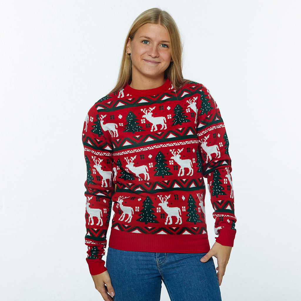 En kvinne har på seg en rød julegenser med reinsdyr og juletrær på.